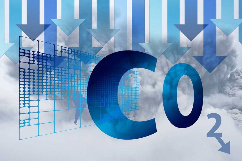 Symbolbild für nachhaltige Logistik: Schriftzug CO2 mit Pfeilen nach unten auf wolkigem Hintergrund