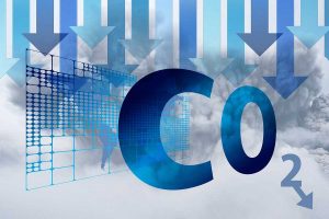 Symbolbild für nachhaltige Logistik: Schriftzug CO2 mit Pfeilen nach unten auf wolkigem Hintergrund