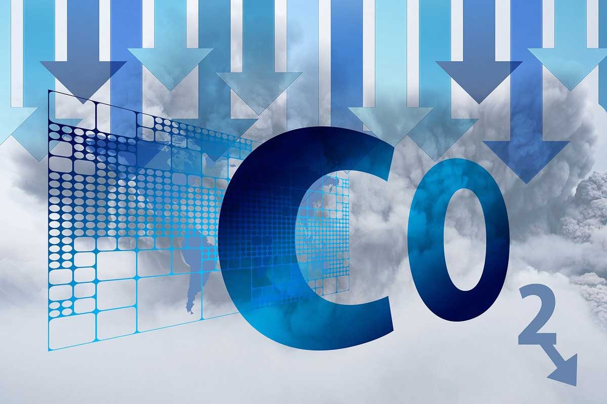 Symbolbild für nachhaltige Logistik: Schriftzug CO2 mit Pfeilen nach unten auf wolkigem Hintergrund
