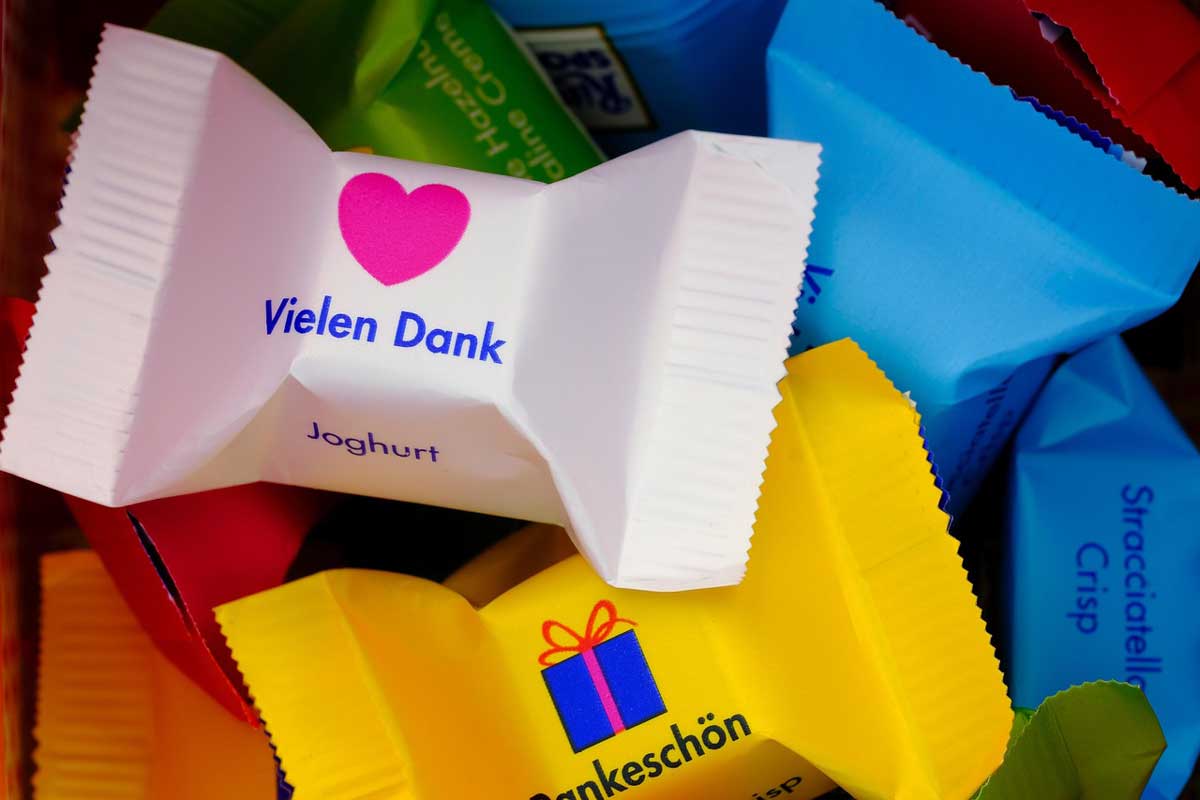 Kundenfeedback: Worte, die uns besonders freuen - P.S.I. Speditions GmbH Symbolbild für ein Dankeschön für ein tolles Kundenfeedback: Kleine, einzeln verpackte Schokowürfel mit Danke-Aufschriften und Herz- und Geschenk-Piktogrammen